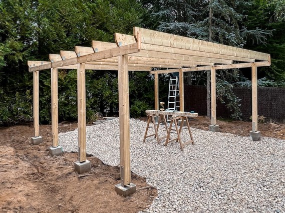 Carport bois pour 2 voitures avec panneau de fond en cours d'installation